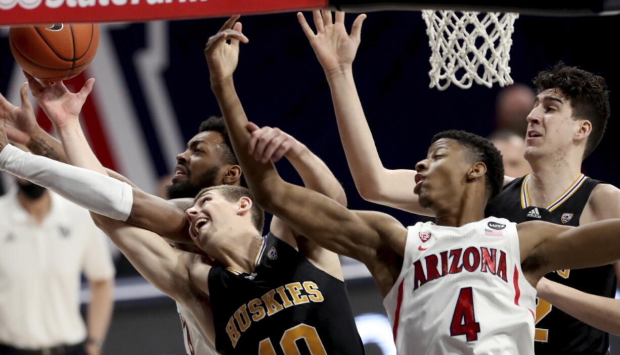 Arizona forward Jordan Brown (21), left, and guard Dalen Terry (4) tangle with Washington guard Erik Stevenson (10) and center Riley Sorn (52) for control of a rebound in the first half of an NCAA college basketball game Saturday, Feb. 27, 2021, in Tucson, Ariz.