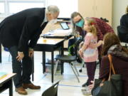 Washington Gov. Jay Inslee, left, talks with a student as teacher Alyson Lykken, center, looks on, Tuesday, Feb. 2, 2021, during a visit to a low-incidence disability classroom at Elk Ridge Elementary School in Buckley, Wash. The school has had some students in classrooms for in-person learning since September of 2020, but other students who attend the school are still learning remotely. Inslee visited the school to observe classrooms and take part in a discussion with teachers and administrators about plans to further open in-person learning in Washington in the future. (AP Photo/Ted S.