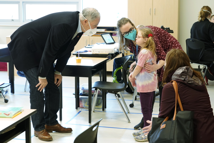 Washington Gov. Jay Inslee, left, talks with a student as teacher Alyson Lykken, center, looks on, Tuesday, Feb. 2, 2021, during a visit to a low-incidence disability classroom at Elk Ridge Elementary School in Buckley, Wash. The school has had some students in classrooms for in-person learning since September of 2020, but other students who attend the school are still learning remotely. Inslee visited the school to observe classrooms and take part in a discussion with teachers and administrators about plans to further open in-person learning in Washington in the future. (AP Photo/Ted S.