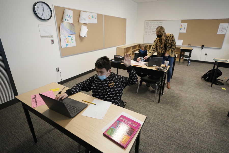 Jonny Velasquez, 9, wears a mask as he raises his hand with a question while working in a fourth-grade classroom, Tuesday, Feb. 2, 2021, at Elk Ridge Elementary School in Buckley, Wash. The school has had some students in classrooms for in-person learning since September of 2020, but other students who attend the school are still learning remotely. Washington Gov. Jay Inslee visited the school Tuesday to observe classrooms and take part in a discussion with teachers and administrators about plans to further open in-person learning in Washington in the future. (AP Photo/Ted S.