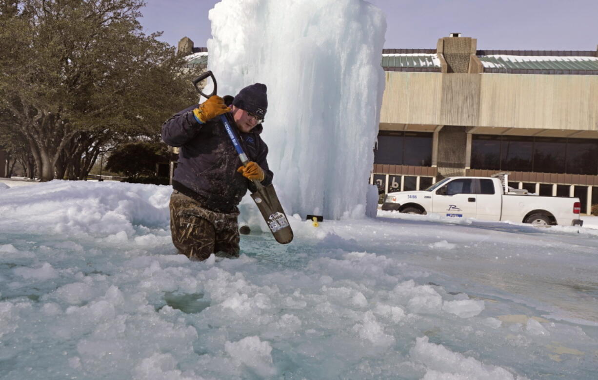 City of Richardson worker Kaleb Love breaks ice on a frozen fountain Tuesday, Feb. 16, 2021, in Richardson, Texas.  Temperatures dropped into the single digits as snow shut down air travel and grocery stores.