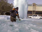 City of Richardson worker Kaleb Love breaks ice on a frozen fountain Tuesday, Feb. 16, 2021, in Richardson, Texas.  Temperatures dropped into the single digits as snow shut down air travel and grocery stores.