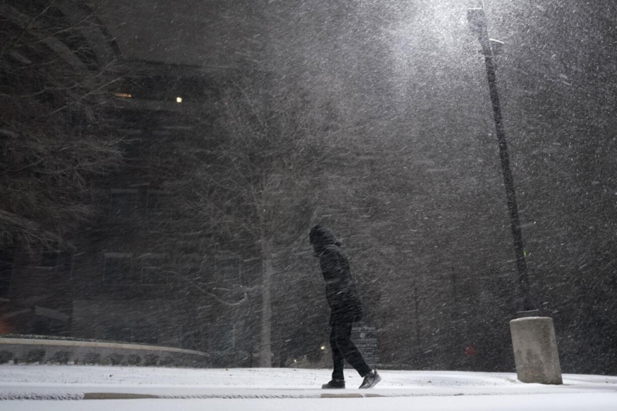 A woman walks through falling snow in San Antonio, Sunday, Feb. 14, 2021. Snow and ice blanketed large swaths of the U.S. on Sunday, prompting canceled flights, making driving perilous and reaching into areas as far south as Texas&#039; Gulf Coast, where snow and sleet were expected overnight.