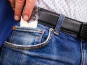 Stock photo of hand pulling a bag of drugs from the front pocket of jeans.
