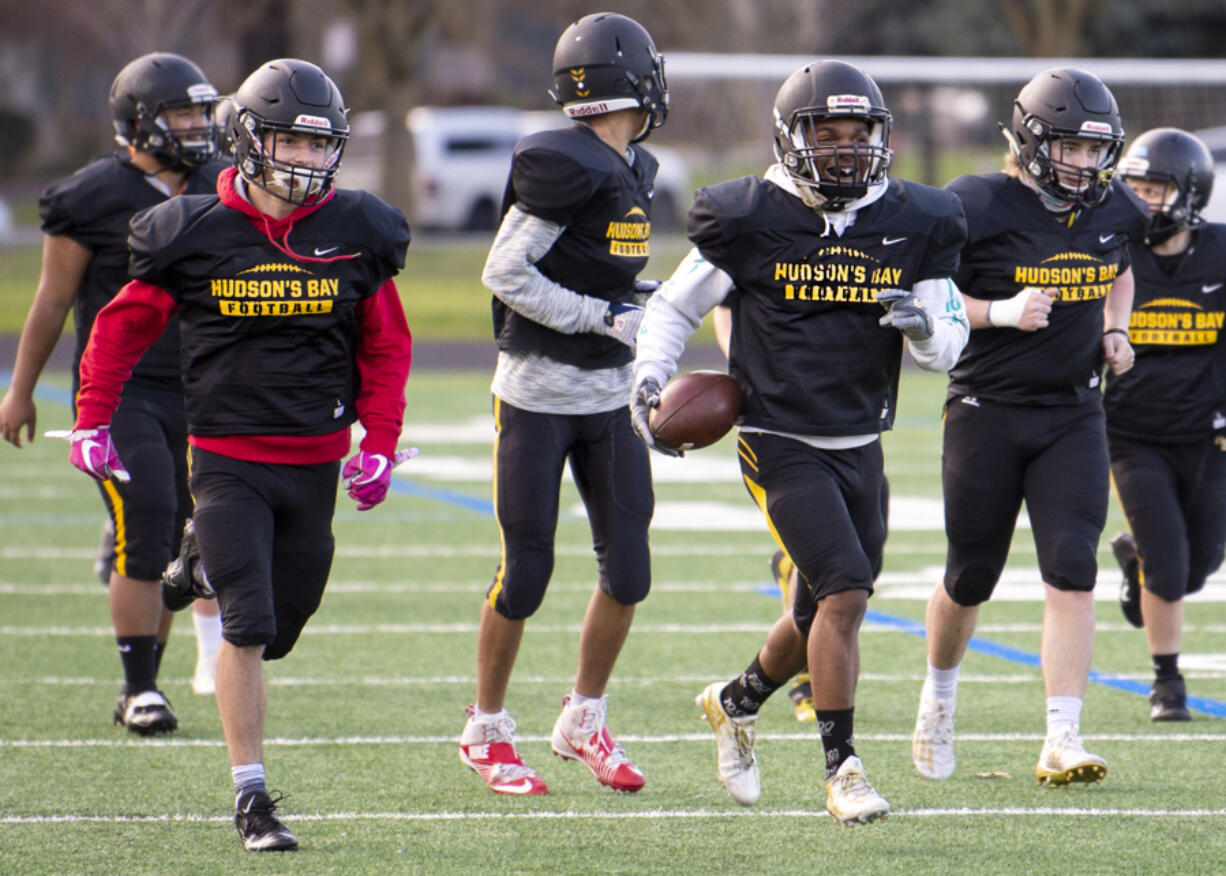 Dylan Damos, left, and Jamarion Hinton, right,  lead of a flock of Eagles as they run back to the huddle on Wednesday, March 10, 2021, at Hudson&#039;is Bay High School. The Eagles have formed a unique bond through their shared experiences, and coach Ray Lions has embraced and cultivated the family-like atmosphere.