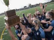 Hockinson senior Kendall McGraw, bottom, lifts the district championship trophy in the air as her team swarms her after the 2A Southwest District Championship on Saturday, March 20, 2021, at District Stadium in Battle Ground. Hockinson won 2-0 to complete a perfect 11-0 season.