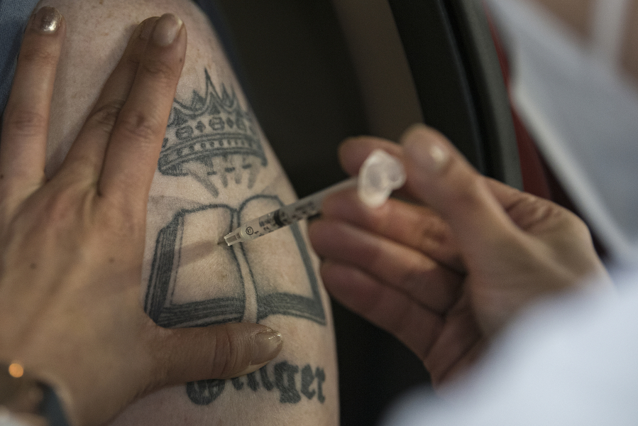 Bob Swenson of Camas receives his first COVID-19 shot at the Clark County Event Center at the Fairgrounds on January 26, 2021. Swenson said he got his tattoo in honor of his mother, Ginger Swenson, and has another on the opposite shoulder to honor his father.