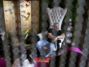 Vancouver resident David Mucci pauses for a portrait at his home, as seen through a beaded curtain. Mucci, an interior designer, contracted COVID-19 in December and still struggles with some symptoms. Also pictured are his cats, Colette, 9, left, and Oscar, 7, foreground.