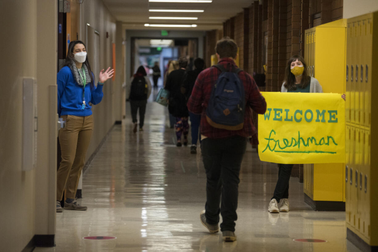 Evergreen High School teachers Anna Capacci, left, and Sophia Lee welcome a member of the freshmen class during an orientation day for incoming ninth-graders on Tuesday.