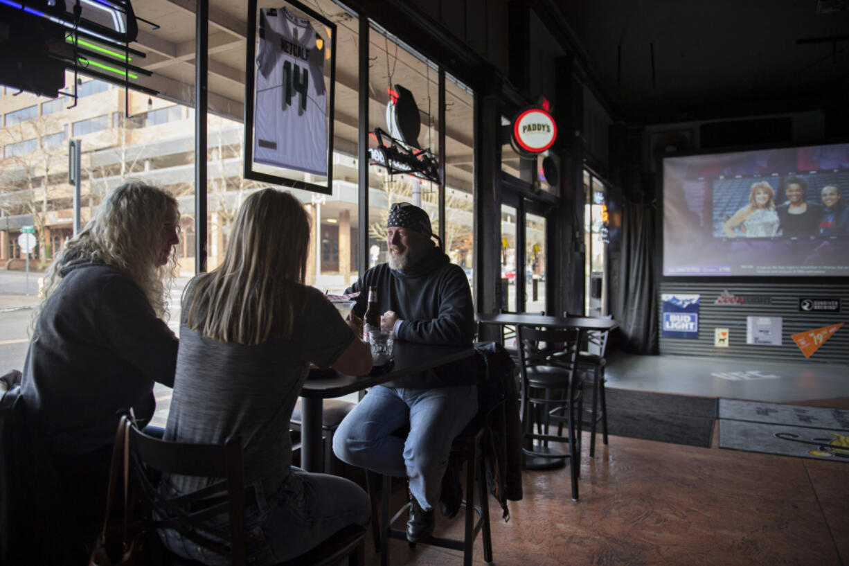 Lynne Reynolds of Vancouver, from left, enjoys food and drinks with Laurie Dean and her husband, Chris, on Monday afternoon at Penalties Sports Pub in downtown Vancouver.