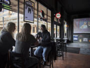 Lynne Reynolds of Vancouver, from left, enjoys food and drinks with Laurie Dean and her husband, Chris, on Monday afternoon at Penalties Sports Pub in downtown Vancouver.