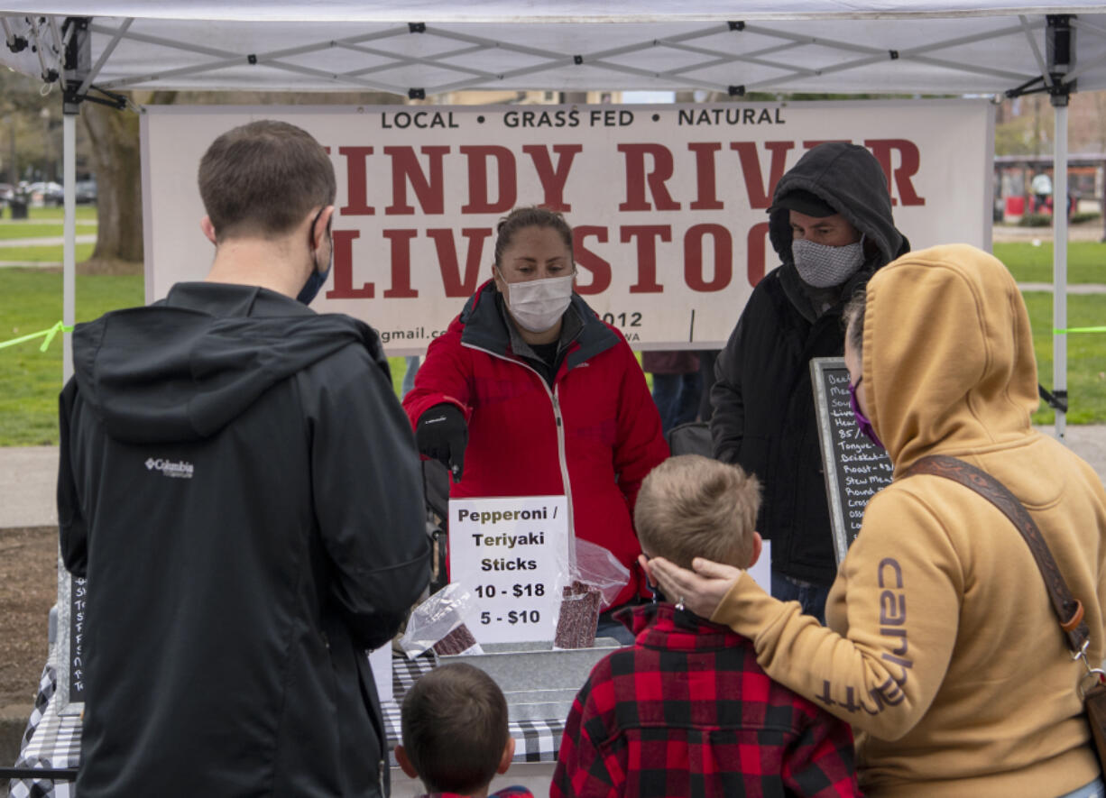 Jocelyn and William Stauffer of Washougal&#039;s Windy River Livestock sell pepperoni sticks to a family on Saturday, opening day for the Vancouver Farmers Market&#039;s 32nd season. Windy River launched years ago as a sideline for the Stauffers, but business has picked up tremendously during the pandemic, they said.