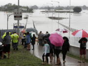 People shelter under umbrellas as they watch the flooded Hawkesbury River in Windsor, northwest of Sydney, New South Wales, Australia, Monday, March 22, 2021. Hundreds of people have been rescued from floodwaters that have isolated dozens of towns in Australia&#039;s most populous state New South Wales and forced thousands to evacuate their homes as record rain continues.