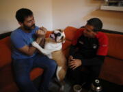 Former Catholic priest Andres Gioeni, right, sits Wednesday with his husband, Luis Iarocci, and their dog Boris after they got home from the bishopric where he started the process of apostasy in Buenos Aires, Argentina.