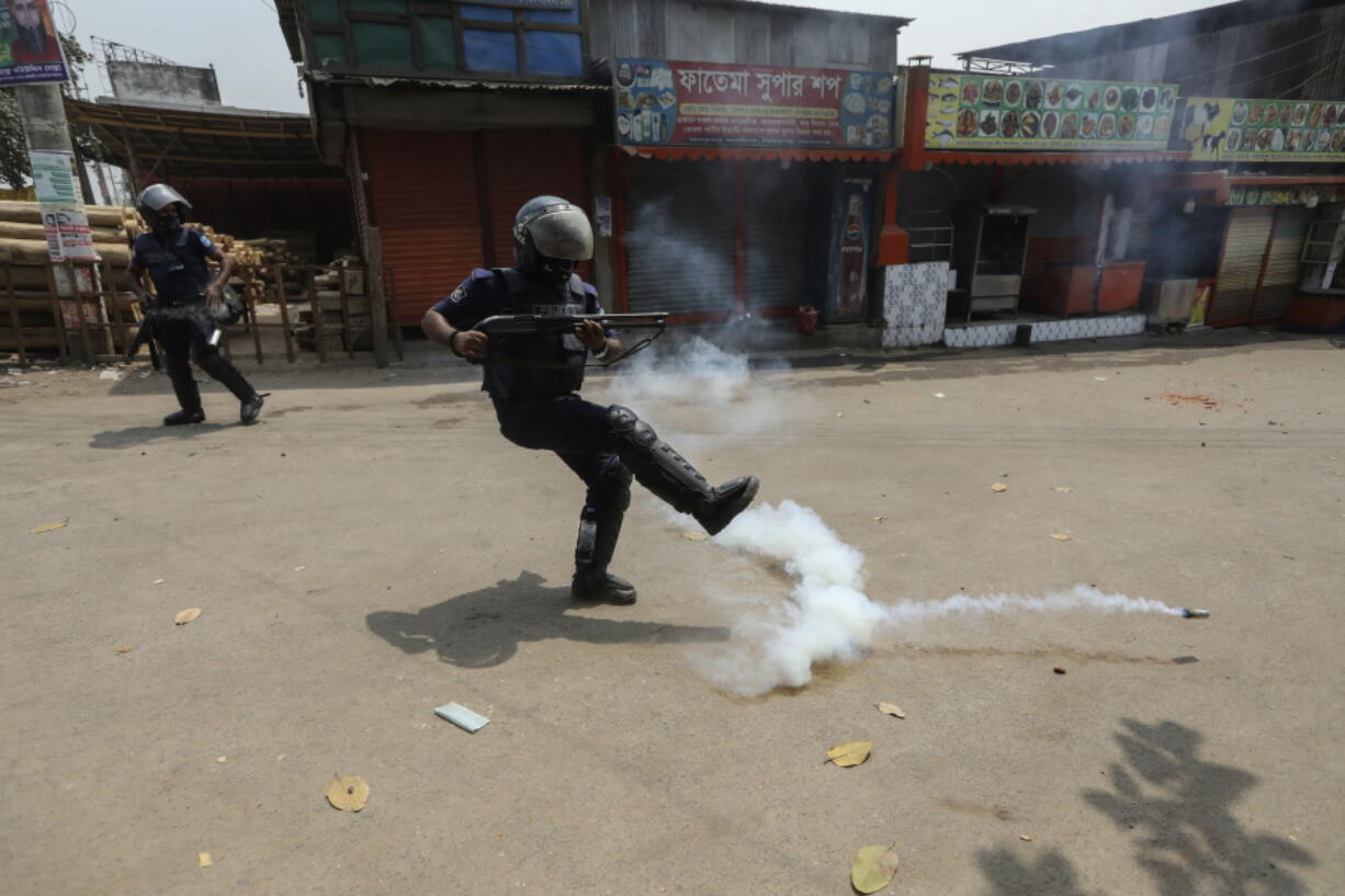 A Bangladeshi policeman kicks away a tear gas shell that misfired while trying to disperse activists of Bangladesh Islamist group Hefazat-e-Islam,  enforcing a daylong general strike in Narayanganj, Bangladesh, Sunday, March 28, 2021. The Islamist group having a strong network of Islamic schools had called for the strike to denounce the deaths of four people in clashes with police involving the visit of Indian Prime Minister Narendra Modi.