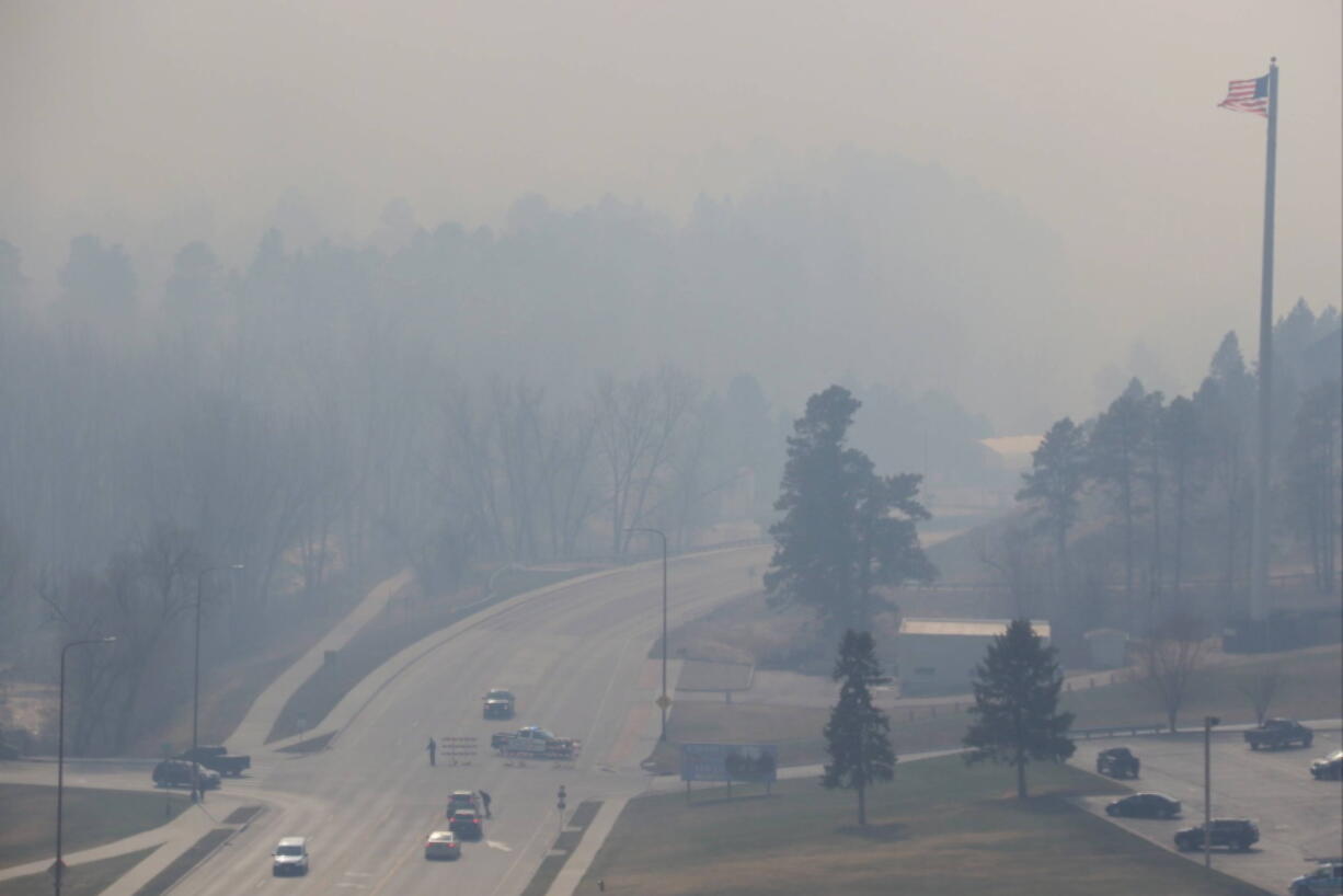 Smoke from a wildfire in the Black Hills of South Dakota blankets an area on the outskirts of Rapid City, S.D., where police set up a roadblock on Monday, March 29, 2021. There were at least three wildfires west that were burning west of Rapid City on a day when wind gusts ranged from 50 to 72 mph. The Pennington County Sheriff&#039;s Office said at least 400 homes had been evacuated and about 250 firefighters were battling the blaze that started near the town of Nemo.