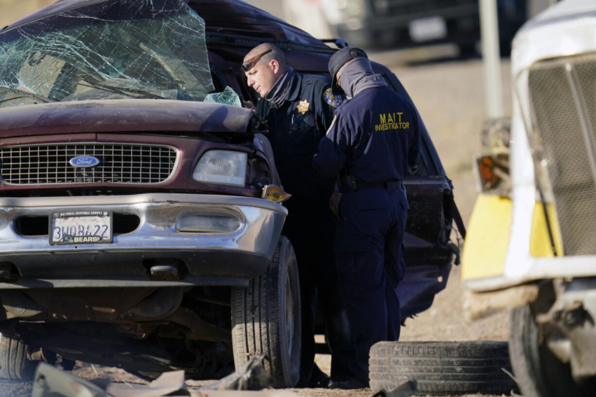 Law enforcement officers sort evidence and debris at the scene of a deadly crash in Holtville, Calif., on Tuesday, March 2, 2021. Authorities say a semi-truck crashed into an SUV carrying 25 people on a Southern California highway, killing at least 13 people.