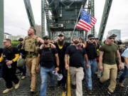 FILE - In this Aug. 17, 2019 file photo organizer Joe Biggs, in green hat, and Proud Boys Chairman Enrique Tarrio, holding megaphone, march with members of the Proud Boys and other right-wing demonstrators march across the Hawthorne Bridge during a rally in Portland, Ore.  Proud Boys &quot;thought leader&quot; and organizer Joseph Biggs agreed to provide the FBI with information about &quot;Antifa networks&quot; in Florida and elsewhere after an agent contacted him in late July 2020 and arranged to meet at a restaurant, Biggs&#039; lawyer, J. Daniel Hull, wrote Monday, March 29, 2021,  in a court filing.