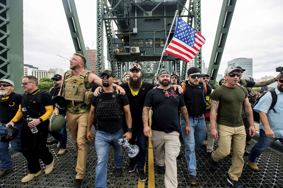 FILE - In this Aug. 17, 2019 file photo organizer Joe Biggs, in green hat, and Proud Boys Chairman Enrique Tarrio, holding megaphone, march with members of the Proud Boys and other right-wing demonstrators march across the Hawthorne Bridge during a rally in Portland, Ore.  Proud Boys &quot;thought leader&quot; and organizer Joseph Biggs agreed to provide the FBI with information about &quot;Antifa networks&quot; in Florida and elsewhere after an agent contacted him in late July 2020 and arranged to meet at a restaurant, Biggs&#039; lawyer, J. Daniel Hull, wrote Monday, March 29, 2021,  in a court filing.