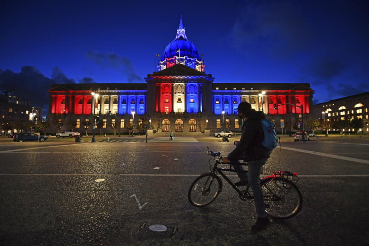 A bicyclist stops to admire the red, white and blue lights illuminating San Francisco City Hall in San Francisco, Calif., Friday, Nov. 6, 2020. Congress is beginning debate on the biggest overhaul of U.S. elections law in a generation. Legislation from Democrats would touch virtually every aspect of the electoral process -- striking down hurdles to voting, curbing partisan gerrymandering and curtailing big money in politics. Republicans see those very measures as a threat that would limit the power of states to conduct elections and ultimately benefit Democrats.