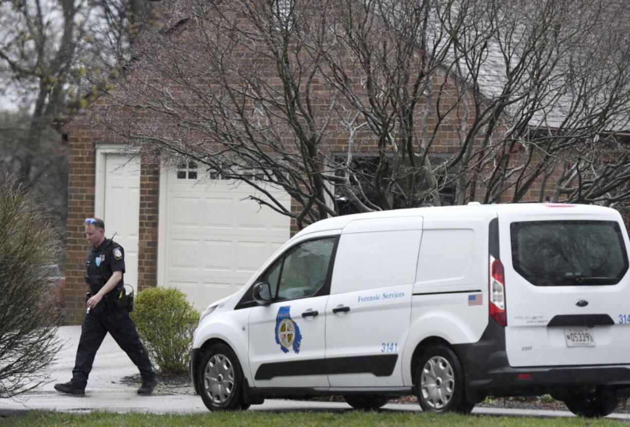 A police officer walks away from a home where at least two people were found dead in Baldwin, Md., on Sunday, March 28, 2021. Authorities say the parents of the suspect in a deadly convenience store shooting and apartment fire were found shot to death in the home.