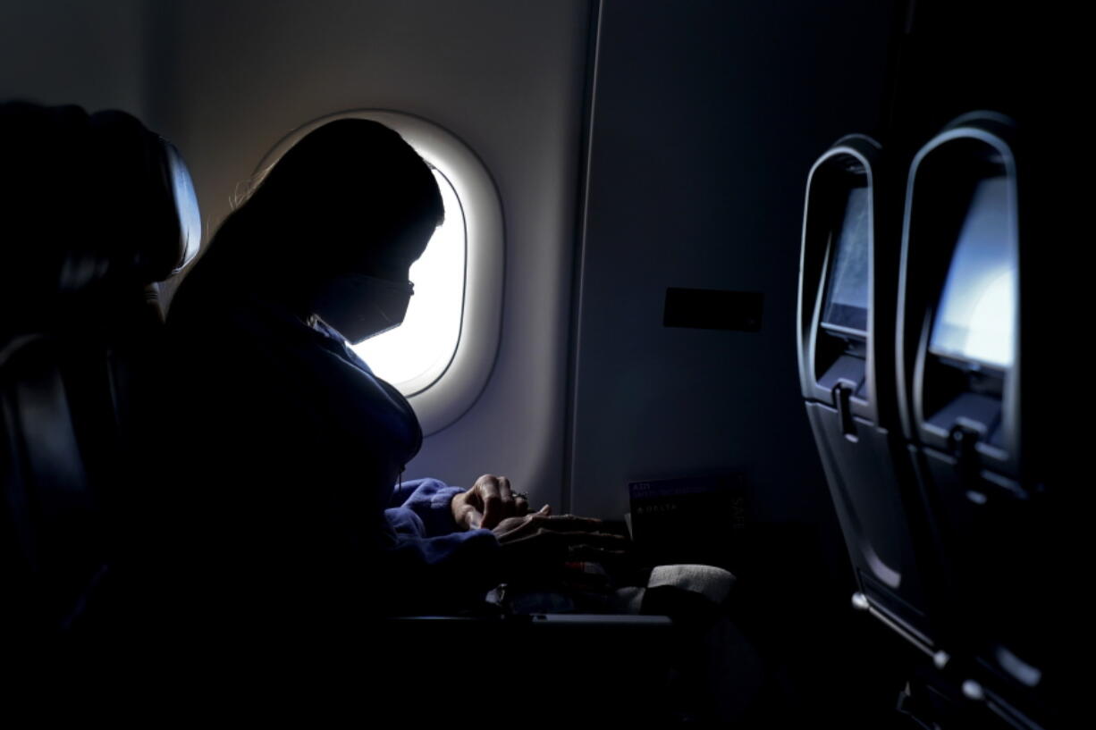 FILE - In this Wednesday, Feb. 3, 2021, file photo, a passenger wears a face mask she travels on a Delta Air Lines flight after taking off from Hartsfield-Jackson International Airport in Atlanta.  Delta Air Lines will stop blocking middle seats in May, meaning that no more U.S. airlines will limit capacity on flights to reduce the risk of spreading COVID-19. Delta&#039;s announcement Wednesday, March 31,  reverses a policy that had been in place since last April.