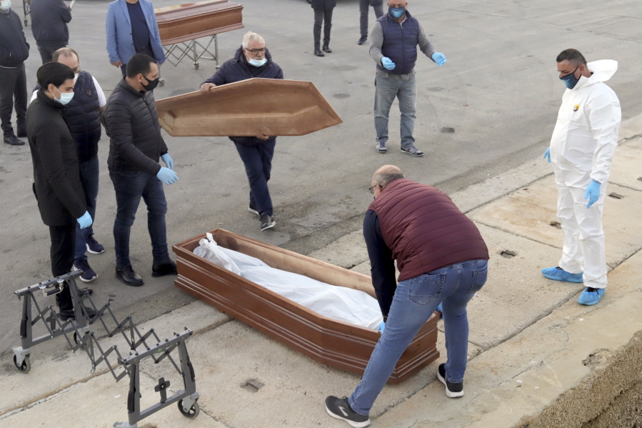 FILE - In this Saturday, Nov. 14, 2020 file photo, a bag containing the body of a migrant who died at sea is placed in a coffin after being disembarked from the Spanish humanitarian rescue ship Open Arms, which was carrying over 200 migrants rescued in the Mediterranean Sea, at the Sicilian port of Trapani, southern Italy. Though the number of migrants and asylum seekers reaching Europe in 2020 is the lowest it has been in the past decade, deaths and disappearances on sea routes to the continent remained alarmingly high with only a small percentage of bodies being recovered according to a report released Friday, March 25, 2021 by UN&#039;s migration agency.