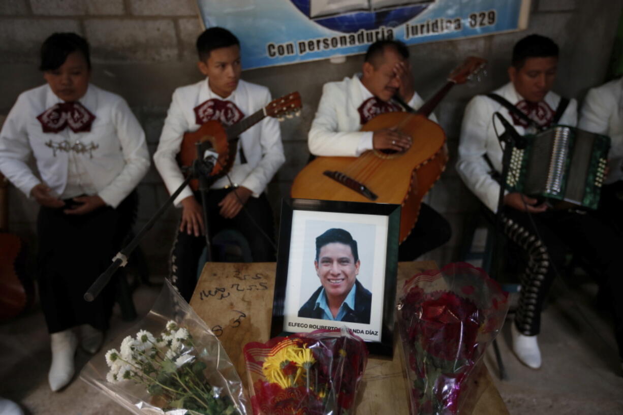 A framed portrait of Elfego Miranda Diaz, one of Guatemalan migrants who was killed near the U.S.-Mexico border in January, sits on top of the coffin that contains his remains during a wake in his home in Comitancillo, Guatemala, Saturday, March 13, 2021. Thousands of residents of this Guatemalan town turned out Friday night amid tears and applause to receive the remains of 16 of their own, found piled in a charred pickup truck in Camargo, across the Rio Grande from Texas.