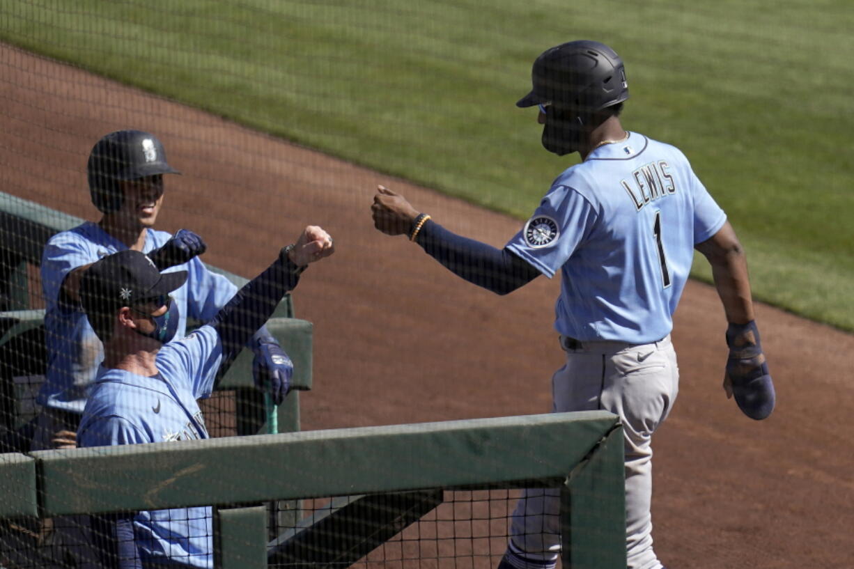 Seattle Mariners&#039; Kyle Lewis (1) gets fist-bumps from manager Scott Servais, left, and a teammate as Lewis returns to the dugout after scoring against the Chicago White Sox during the third inning of a spring training baseball game Friday, March 5, 2021, in Phoenix. (AP Photo/Ross D.