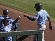 Seattle Mariners&#039; Kyle Lewis (1) gets fist-bumps from manager Scott Servais, left, and a teammate as Lewis returns to the dugout after scoring against the Chicago White Sox during the third inning of a spring training baseball game Friday, March 5, 2021, in Phoenix. (AP Photo/Ross D.