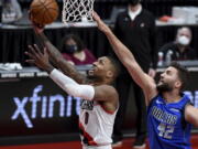 Portland Trail Blazers guard Damian Lillard, left, drives to the basket past Dallas Mavericks forward Maxi Kleber during the first half of an NBA basketball game in Portland, Ore., Friday, March 19, 2021.