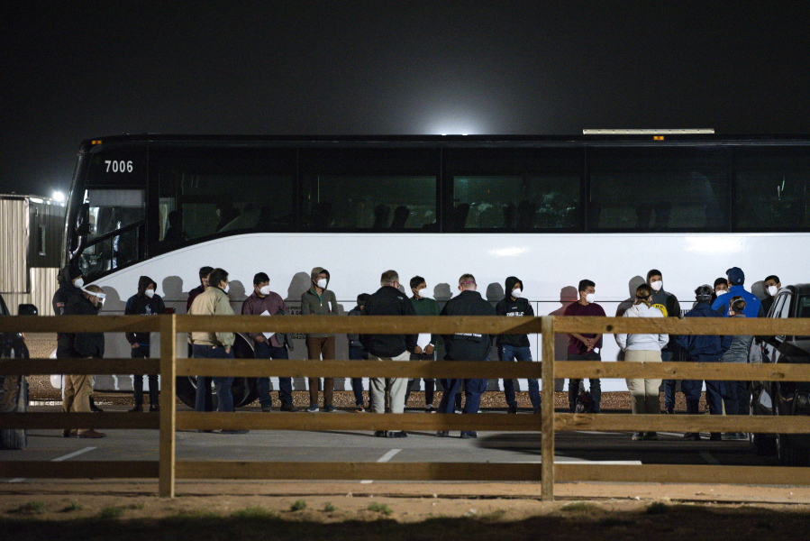 FILE - In this Sunday, March 14, 2021, file photo, migrant children and teenagers are processed after entering the site of a temporary holding facility south of Midland, Texas. The Biden administration is not requiring FBI fingerprint background checks of caregivers at its rapidly expanding network of emergency sites to hold thousands of immigrant teenagers. That alarms child welfare experts who say the waiver compromises safety.