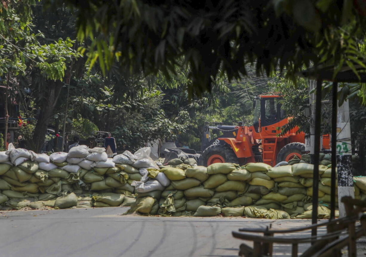 A man watches as soldiers use a bulldozer to remove sandbag barricades put in place by anti-coup protesters to protect them from security forces in Mandalay, Myanmar, Thursday, March 18, 2021.