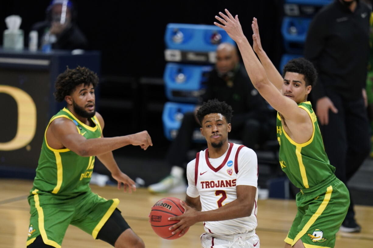 Southern California guard Tahj Eaddy (2) drives between Oregon guard LJ Figueroa, left, and guard Will Richardson, right, during the first half of a Sweet 16 game in the NCAA men&#039;s college basketball tournament at Bankers Life Fieldhouse, Sunday, March 28, 2021, in Indianapolis.