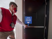 An usher places a sign near the fans&#039; entrance to remind them to wear face coverings for a first-round game in the NCAA men&#039;s college basketball tournament, Saturday, March 20, 2021, at Assembly Hall in Bloomington, Ind.