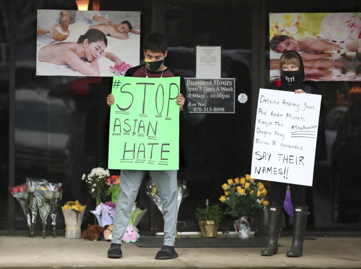 After dropping off flowers Jesus Estrella, left, and Shelby stand in support of the Asian and Hispanic community outside Young&#039;s Asian Massage Wednesday, March 17, 2021, in Acworth, Ga. Asian Americans, already worn down by a year of racist attacks fueled by the pandemic, are reeling but trying to find a path forward in the wake of the horrific shootings at three Atlanta-area massage businesses that left eight people dead, most of them Asian women.