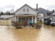 Catherine Castle stands on the porch of her home in downtown Paintsville, Ky., as floodwaters approach on Monday, March 1, 2021.  (Ryan C.