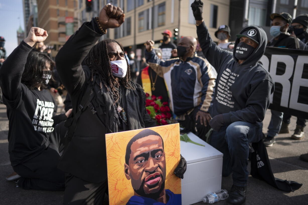 Cortez Rice, left, of Minneapolis, sits with others in the middle of Hennepin Avenue on Sunday, March 7, 2021, in Minneapolis, Minn., to mourn the death of George Floyd a day before jury selection is set to begin in the trial of former Minneapolis officer Derek Chauvin, who is accused of killing Floyd.