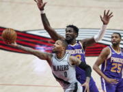 Portland Trail Blazers guard Damian Lillard, left, shoots next to Phoenix Suns center Deandre Ayton during the second half of an NBA basketball game in Portland, Ore., Thursday, March 11, 2021.