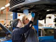 Clark College automotive technology professor Tonia Haney prepares a student for removing a vehicle’s engine during a lab class.