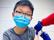 In this Dec. 22, 2020, photo, provided by Richard Chung, his son Caleb Chung receives the first dose of Pfizer coronavirus vaccine or placebo as a trial participant for kids ages 12-15, at Duke University Health System in Durham, N.C. Pfizer says its COVID-19 vaccine is safe and strongly protective in kids as young as 12. The announcement Wednesday, March 31, 2021 marks a step toward possibly beginning shots in this age group before the next school year.