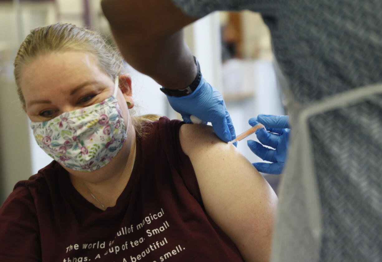 A woman at the Wheatfield surgery is given a 1st shot of the AstraZeneca COVID-19 vaccine by Dr Christian Owusu-Yianoma in Luton, England, Thursday, March 18, 2021.