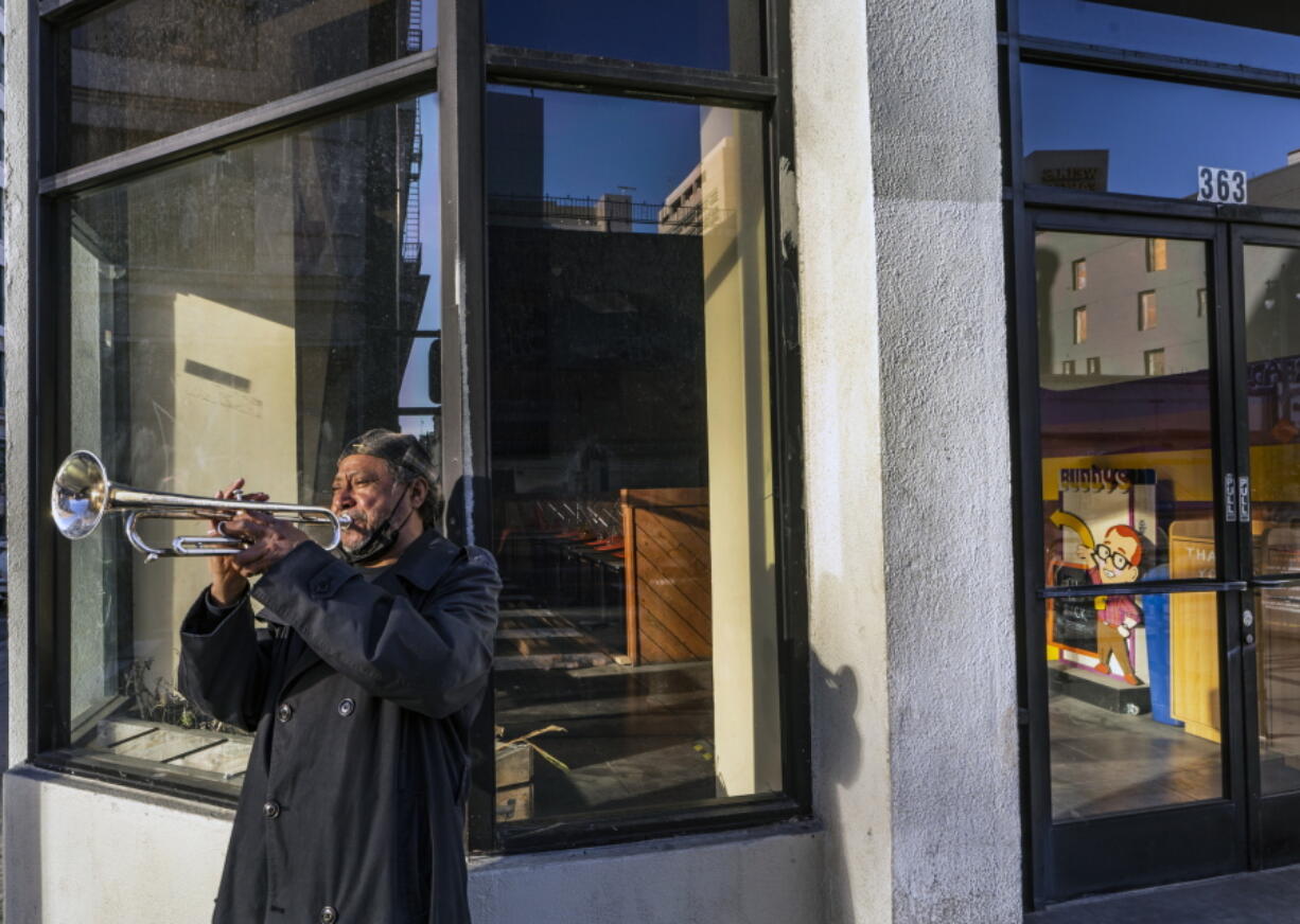 FILE - In this Feb. 5, 2021, file photo, street musician Roberto Hernandez, originally from El Salvador, plays &quot;Lambada&quot; on his trumpet outside Buddy&#039;s, a restaurant temporarily closed due to the COVID-19 pandemic, in downtown Los Angeles. Los Angeles County could move into the next phase of reopening with fewer restrictions as early as next week, though any actual lifting of coronavirus-related constraints would not happen immediately, health officials said Wednesday, March 3, 2021.