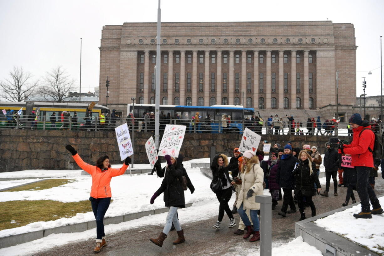 A group of people hold placards during a protest against the Finnish government&#039;s regulations to fight the coronavirus pandemic in Helsinki, Saturday, March 20, 2021. Some 400 protesters gathered peacefully in downtown Helsinki.