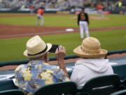 Two older adults, socially distanced, watch a spring training exhibition baseball game between the Pittsburgh Pirates and the Baltimore Orioles on Monday in Bradenton, Fla. (gene j.