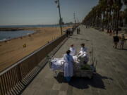 FILE - In this Sept. 4, 2020, file photo, Francisco Espana, 60, is surrounded by members of his medical team as he looks at the Mediterranean sea from a promenade next to the &quot;Hospital del Mar&quot; in Barcelona, Spain. Francisco spent 52 days in the Intensive Care unit at the hospital due to coronavirus, but today he was allowed by his doctors to spend almost ten minutes at the seaside as part of his recovery therapy.