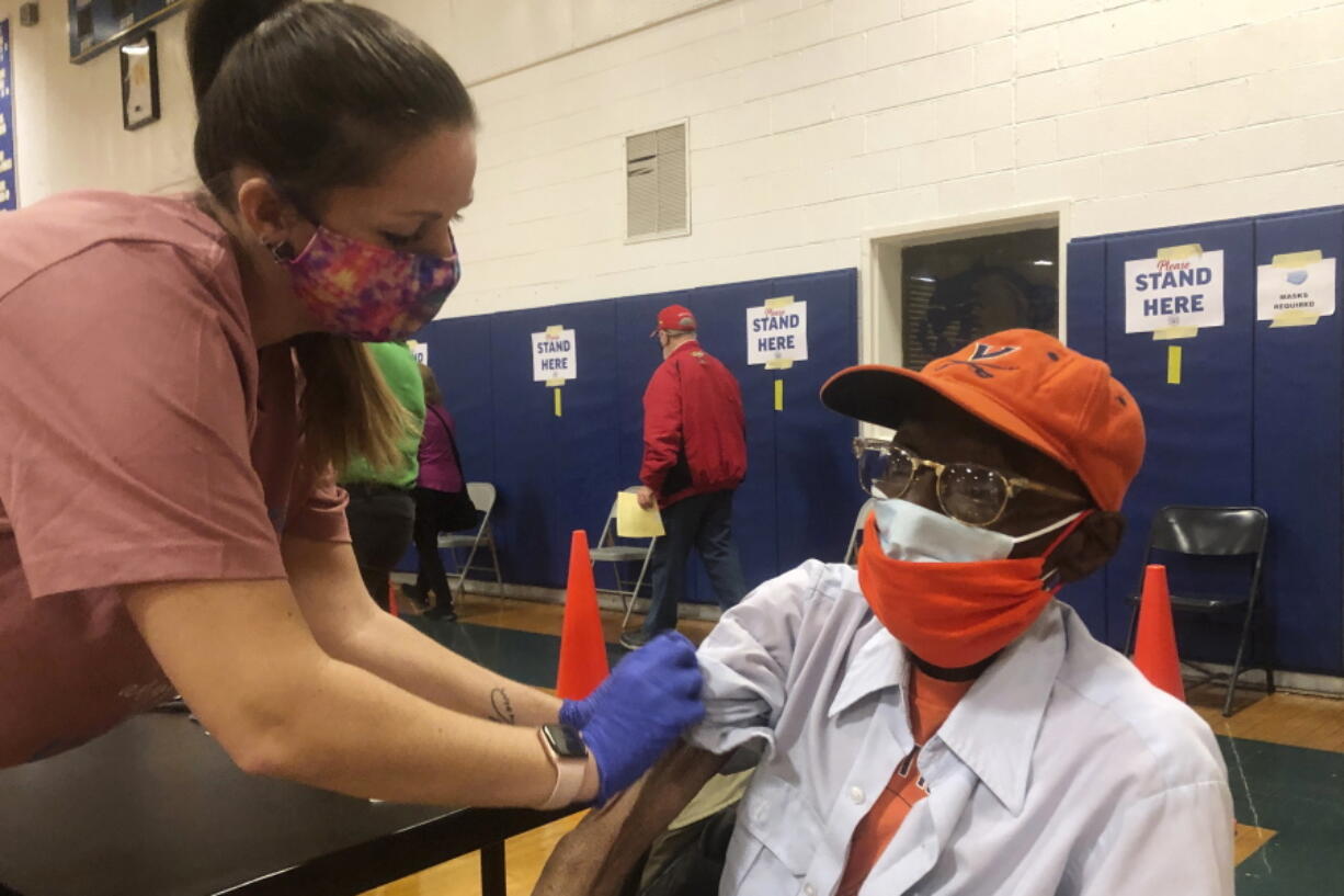 Debbie Monahan, a school nurse, pulls down Charles Robbins&#039; sleeve after giving him his second shot of the coronavirus vaccine at Surry County High School in Dendron, Va., on Saturday Feb. 27, 2021. Getting the coronavirus vaccine has been a challenge for rural counties in the U.S. that lack medical facilities such as a pharmacy or a well-equipped doctor&#039;s office.