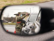 A National Guard soldier directing drivers is reflected in the mirror of a car waiting in a COVID-19 vaccination line Feb. 26, 2021, in Shelbyville, Tenn. Tennessee has continued to divvy up vaccine doses based primarily on how many people live in each county, and not on how many residents belong to eligible groups within those counties.