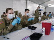 FILE - In this March 9, 2021, file photo, Army health specialists fill syringes with the Pfizer COVID-19 vaccine in Miami. Despite the clamor to speed up the U.S. vaccination drive against COVID-19, the first three months of the rollout suggest faster is not necessarily better.