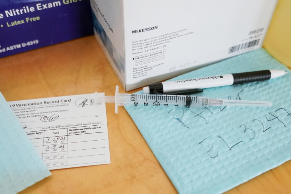 FILE - In this Friday, Jan. 15, 2021 file photo, a syringe filled with the a COVID-19 vaccine is seen alongside its batch number and a patient&#039;s vaccination card at a vaccination site in the East Harlem neighborhood of New York. According to recommendations from an expert panel from three cancer centers in the U.S. published in the journal Radiology on Feb. 24, 2021, anyone getting a mammogram or other cancer check soon after a COVID-19 vaccine should alert doctors, to prevent false alarms from a side effect. Sometimes lymph nodes, especially in the armpit, swell after the vaccinations. It&#039;s a normal reaction by the immune system but one that might be mistaken for cancer if it shows up on a mammogram or other scan.